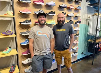 Jim Dwyer and Clifton Trebil-Smith, co-owners of Iowa Running Company in front of a wall of running shoes