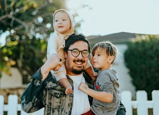 Man in white shirt holding baby and toddler