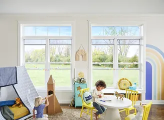 Children playing in a rainbow filled playroom with large open windows