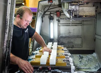 Person wearing a dark tee and safety glasses working with machining equipment