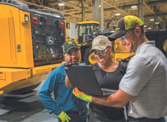 Workers in the John Deere factory looking at a laptop