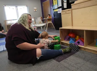 Women in a daycare setting playing with a baby