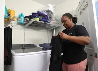 Woman holding up a shirt while doing laundry