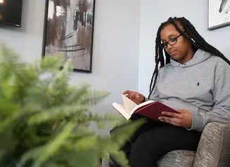 Woman reading a book while sitting in an armchair