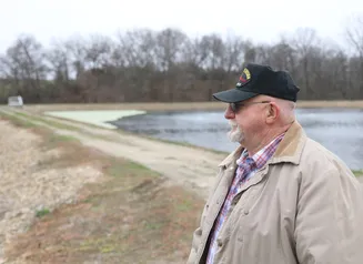 Moravia's mayor, wearing a baseball cap, stands in front of the city lagoon