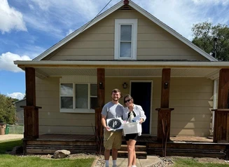a couple standing in front of their home