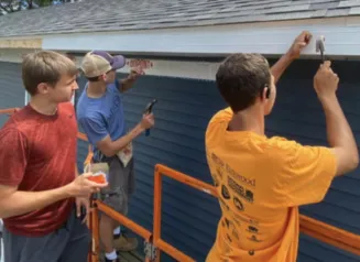 three people working on the exterior of a house