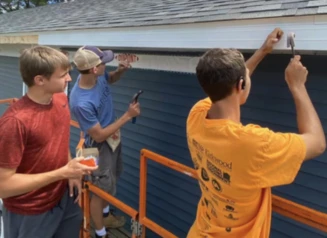 three people working on the exterior of a house