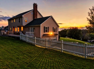 single family home with a large yard and fence at sunset