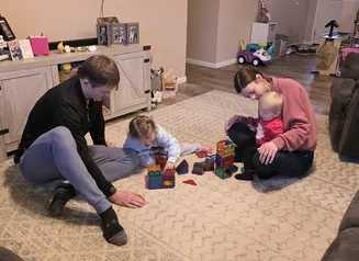 Mom and Dad stacking blocks with two children.