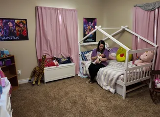 Mom feeding baby with a bottle on a bed.