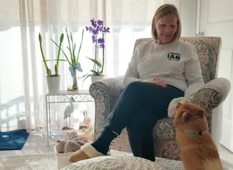 Woman sitting on couch with dog below.