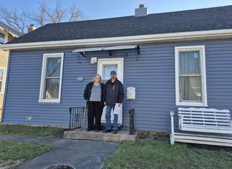 Couple standing in front of blue house with new roof 