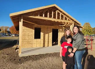 Family standing in front of newly built house.
