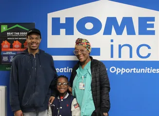 Family standing in front of HOME Inc. wall