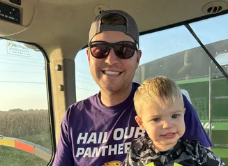 Father and son riding on tractor.
