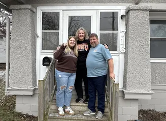 Family standing in front of home with keys