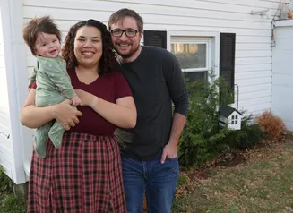 family of three outside of house