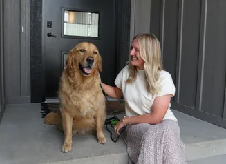Girl with dog outside on front proch