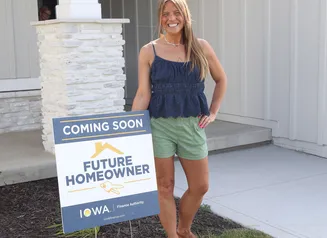 female standing in front of  sold sign