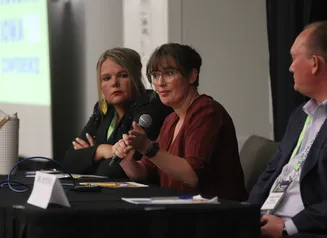 three individuals presenting at a black table