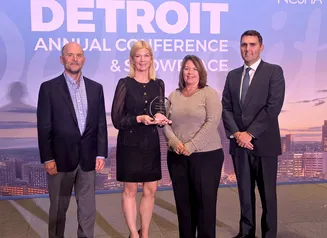 four people standing on a stage accepting an award