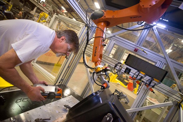 Man working in a factory with a robotic arm