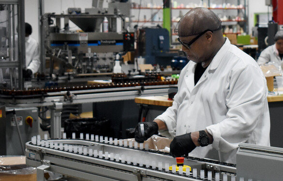 Worker wearing gloves and a hairnet on the assembly line at Eco Lips