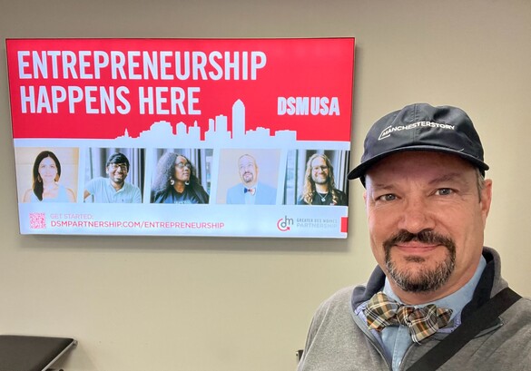 Jason Gross in front of an electronic billboard that reads Entrepreneurship Happens Here