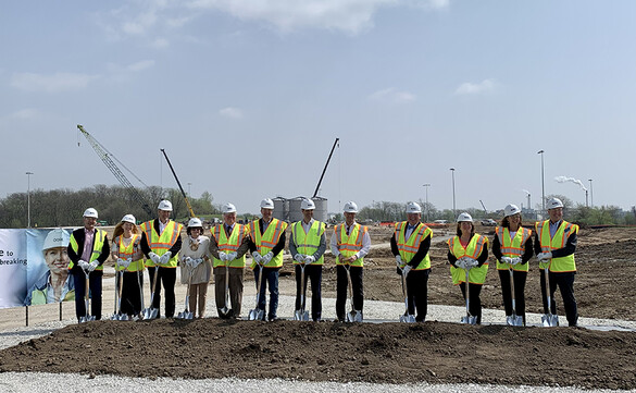 People in vests and hard hats with shovels breaking ground