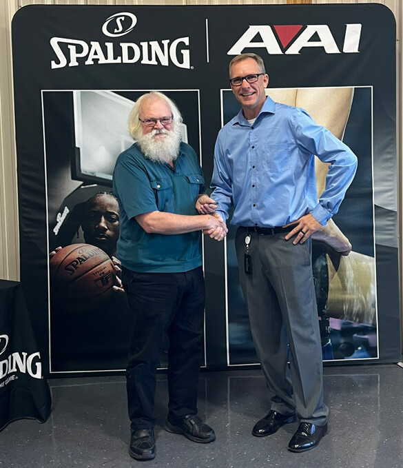 Steve Kohl with an AAI/Spalding employee in front of a banner with the company name and logos