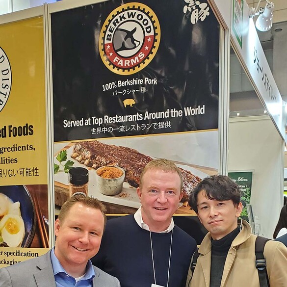 Nick Jones, CEO of Berkwood Farms with Japanese partners in front of a sign advertising Berkfood Farms in English and Japanese