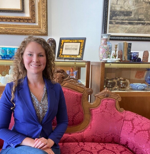Erin Naylor, owner of Heron Kross sitting on an antique pink couch