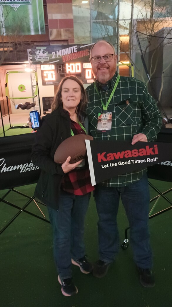 Gina and Kevin Nelson of Holtz Service and Small Engine holding a Kawasaki sign