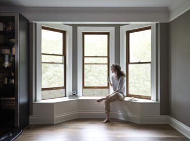 Woman sitting on a window seat drinking from a mug