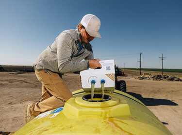 Man in a hat pouring liquid into a yellow tank