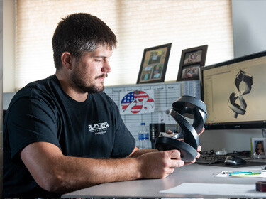 Person holding a plastic molded object sitting at a desk