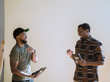 Pernell Cezar Jr. and Rod Johnson talking while holding tablets