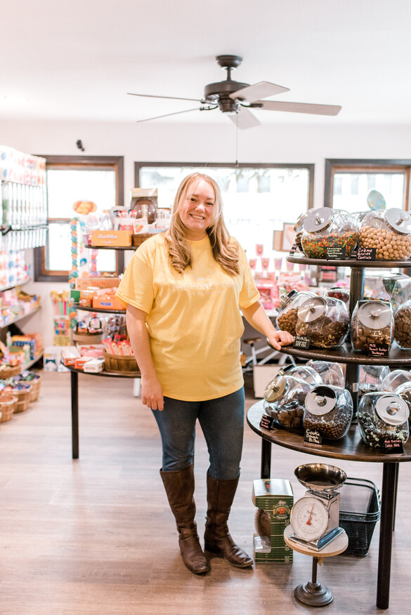 Owner of The Honey Den standing by a candy display