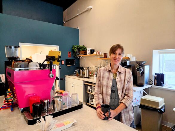 a woman standing behind the counter of a coffee shop