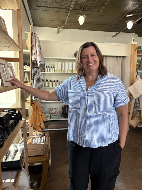 a woman smiling and standing next to a retail store shelf
