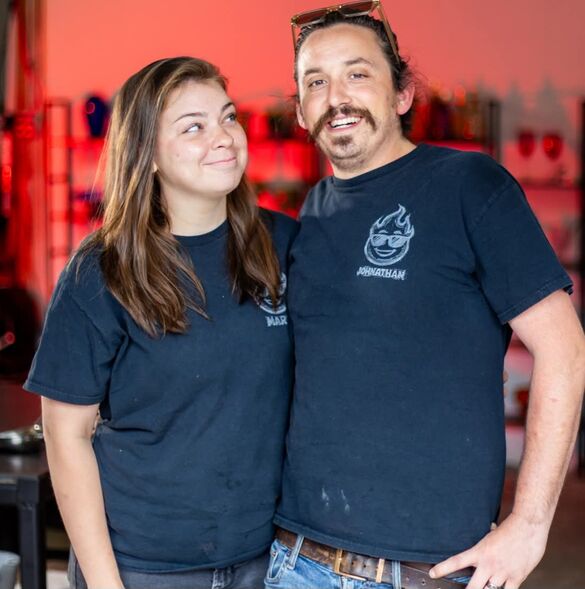 two people wearing black t shirts standing in front of a red wall