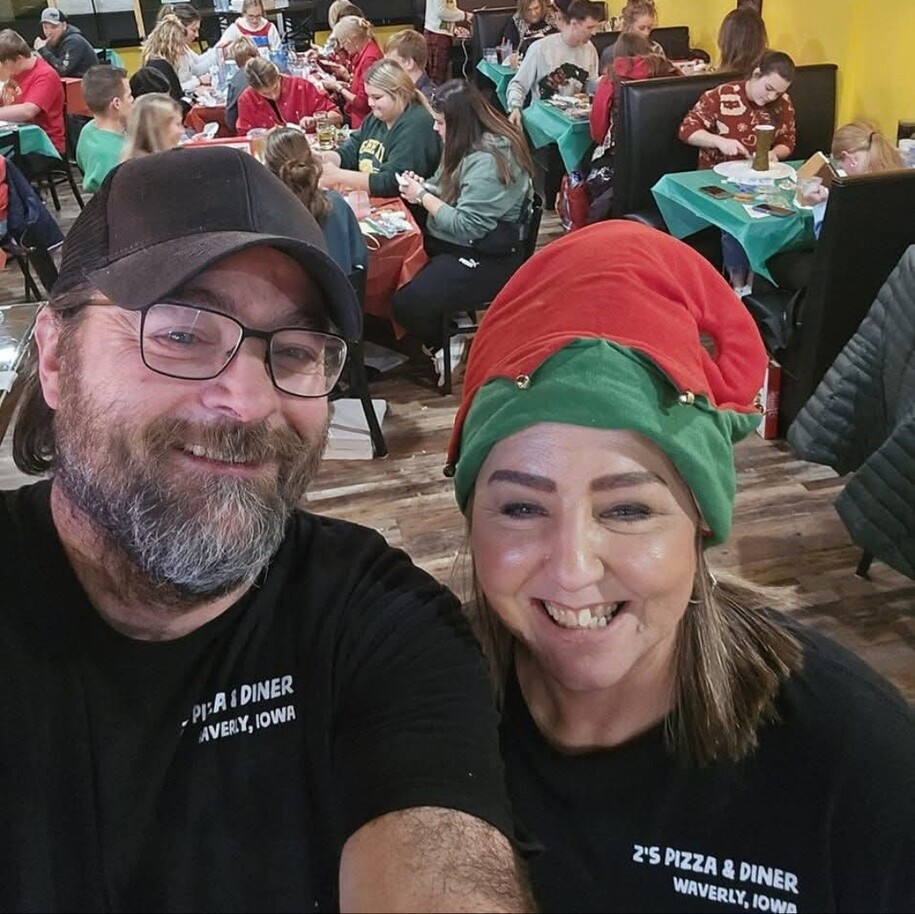 two people wearing z's pizza t shirts in a restaurant