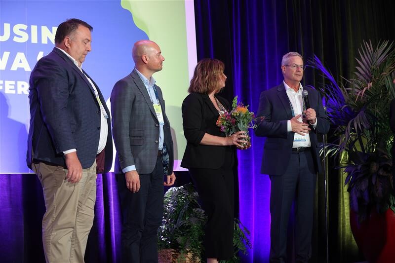four people standing on a stage accepting an award